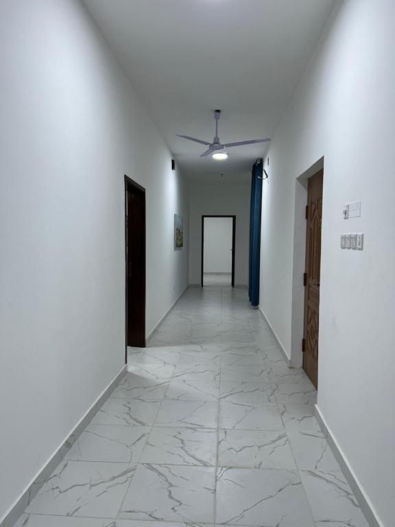 a hallway with white walls and a tile floor at Al Shiya Chalet in Sur