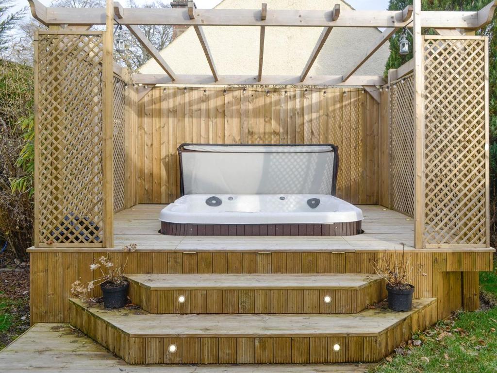 a bath tub in a wooden gazebo at Burnbrae Cottage in Bridgend of Lintrathen