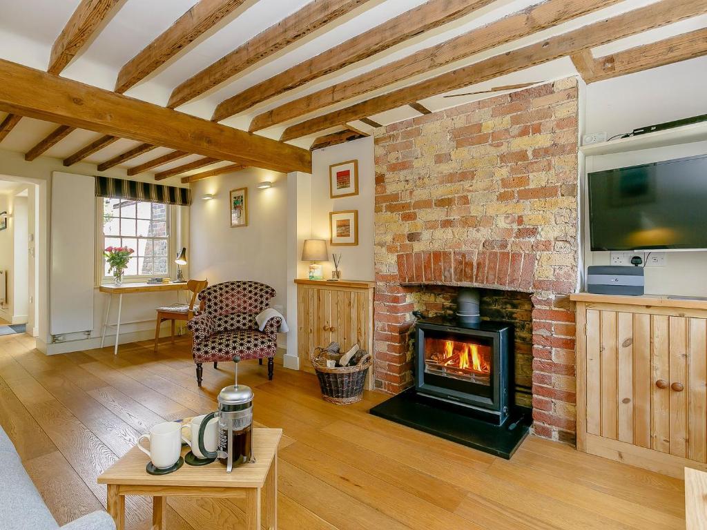 a living room with a fireplace and a tv at Rose Cottage in Poynings