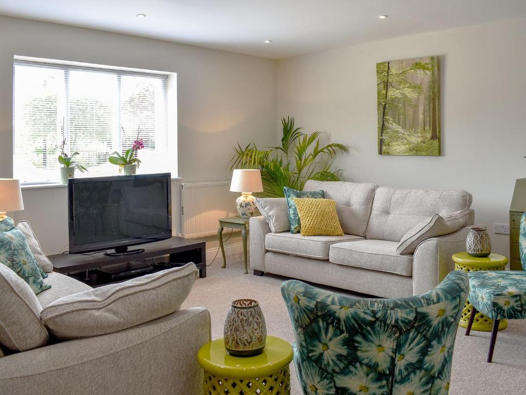 uma sala de estar com 2 sofás e uma televisão de ecrã plano em Serendipity em Ferndown