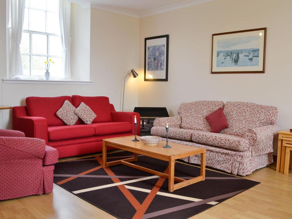 a living room with two red couches and a coffee table at Sunset Song in Arbuthnott