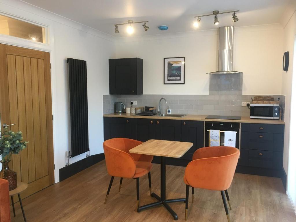 a kitchen with orange chairs and a wooden table at Little Oaks in Pembrokeshire
