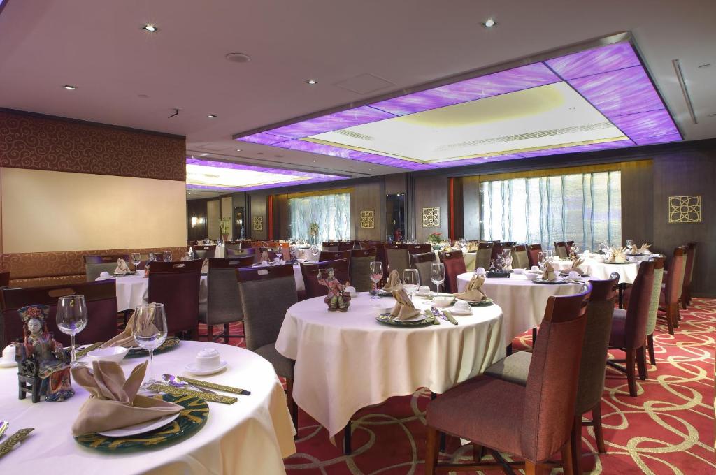 una sala da pranzo con tavoli e sedie bianchi di Metropark Hotel Kowloon a Hong Kong