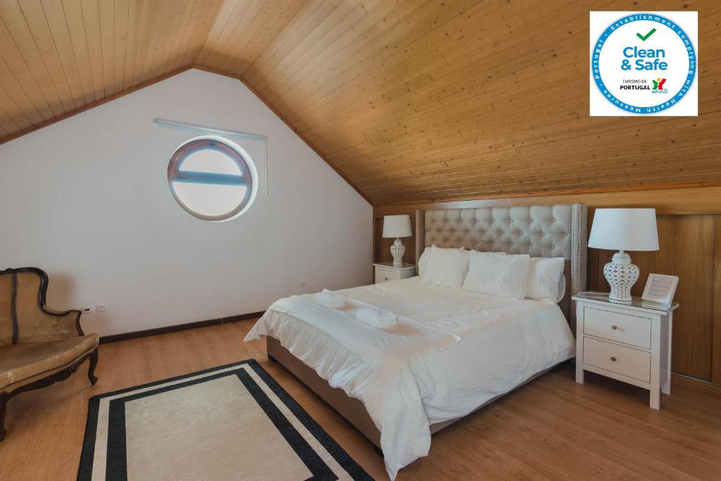 sypialnia z białym łóżkiem i drewnianym sufitem w obiekcie Retiro da Serra w mieście Penhas da Saúde