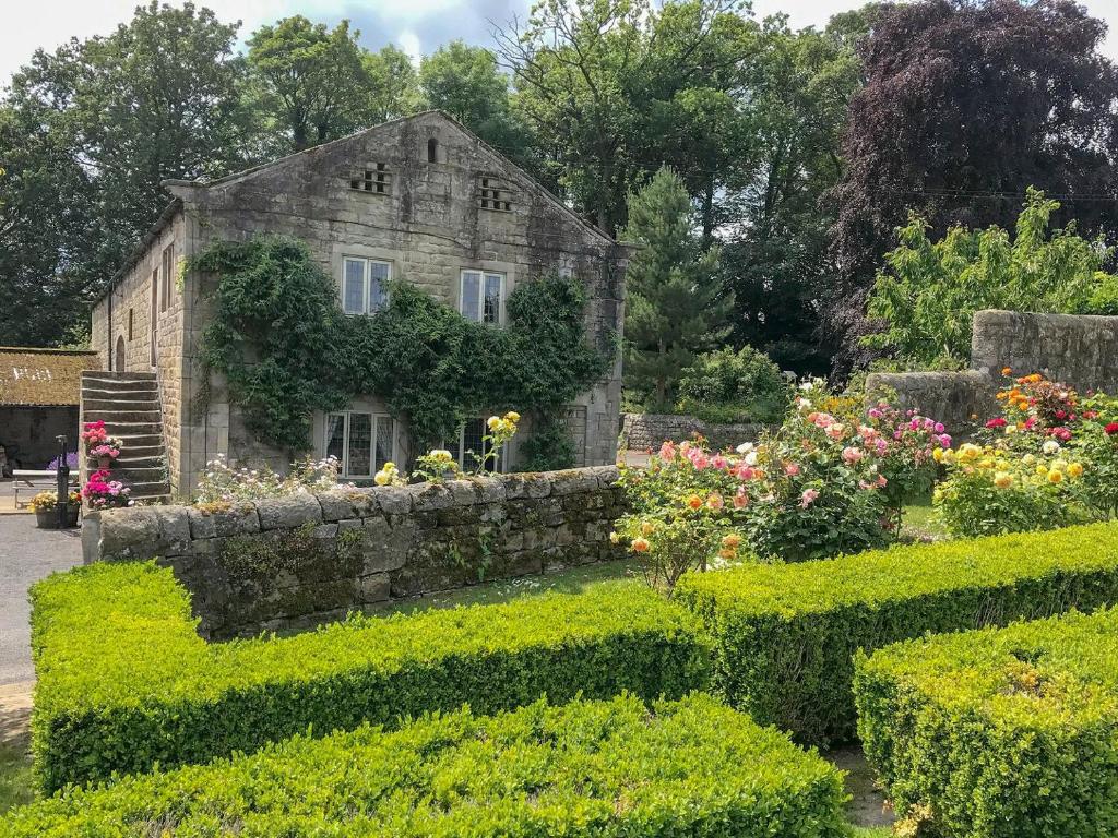 an old stone house with flowers in a garden at The Dovecote in Birstwith