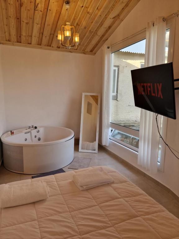 a bathroom with a tub and a tv and a window at Aprosmeno Jacuzzi House 4 in Agros