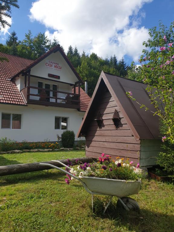 une maison avec un lit fleuri dans une brouette dans l'établissement Casa Maia, à Cârţişoara