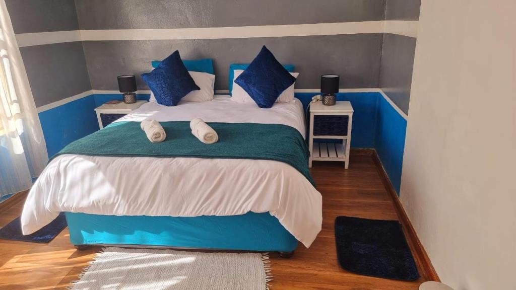 a bedroom with a blue and white bed with blue pillows at Epic Den Lodge in Phuthaditjhaba