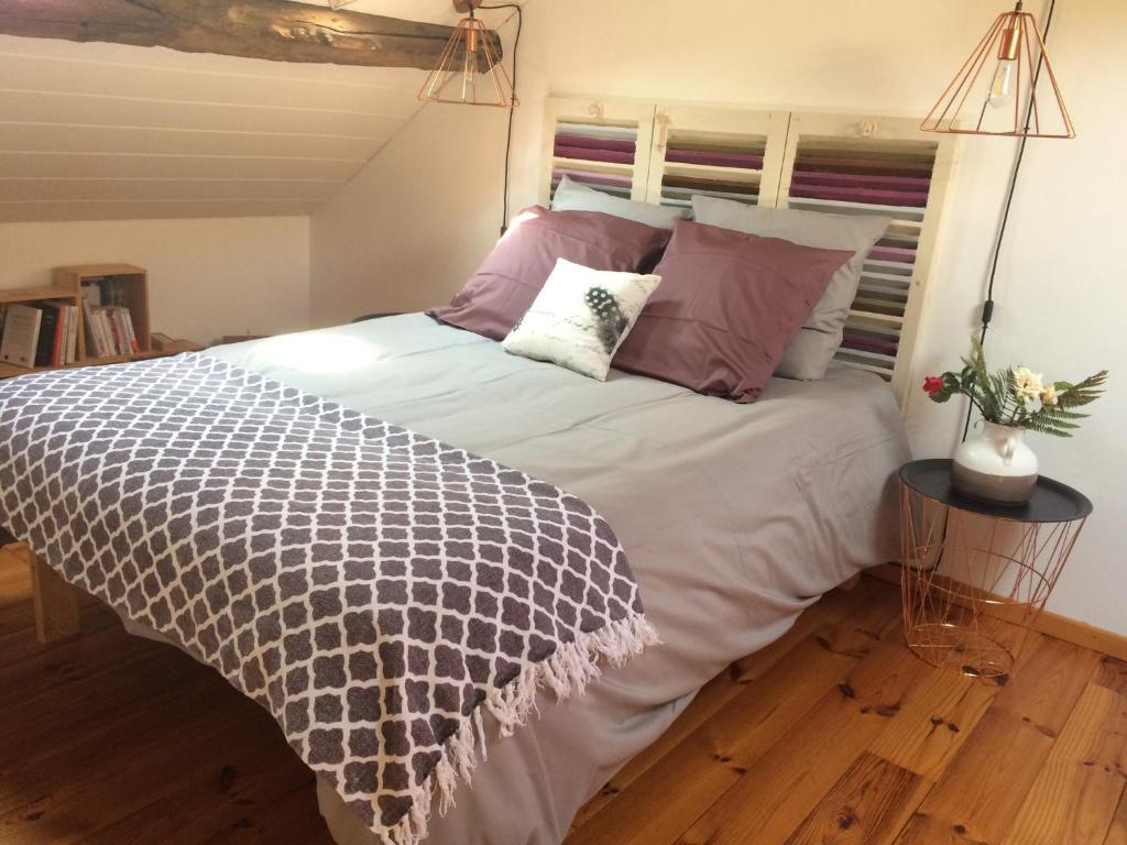 - une chambre avec un grand lit et des oreillers violets dans l'établissement La courtine Etretat maison de pêcheur 2 mn de la mer, à Étretat