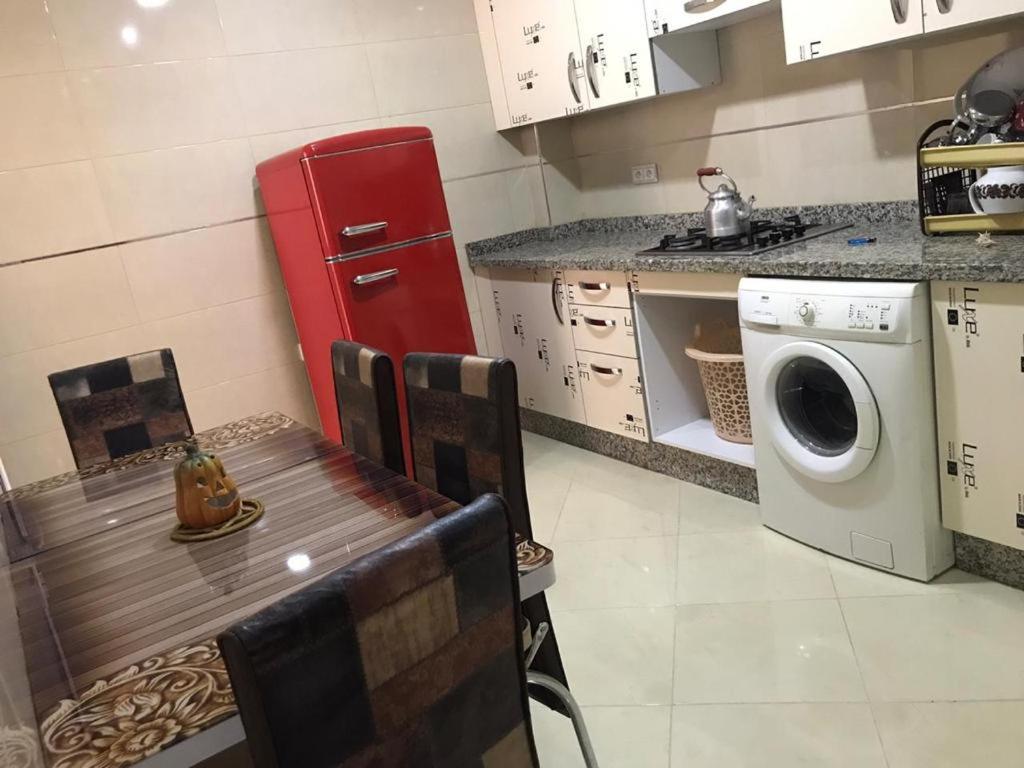 eine Küche mit einem Tisch und einem roten Kühlschrank in der Unterkunft اقامة السعادة in Nador