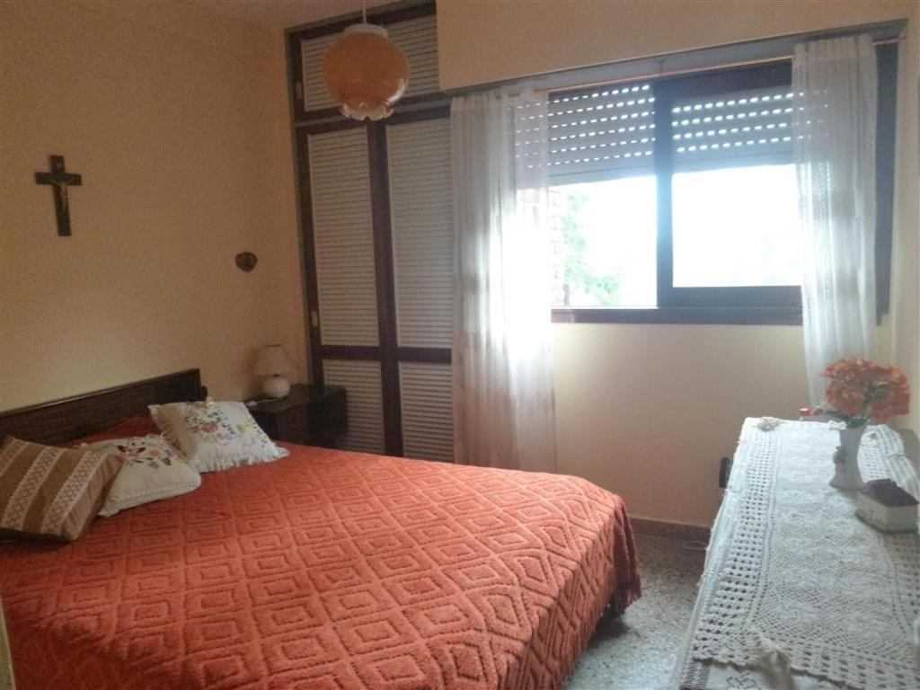 サンベルナルドにあるSan Bernardo, hermoso dpto. a 2 cuadras del mar y 1 del centro para 6 personasのベッドルーム1室(ベッド1台付)、壁に十字架のある窓が備わります。