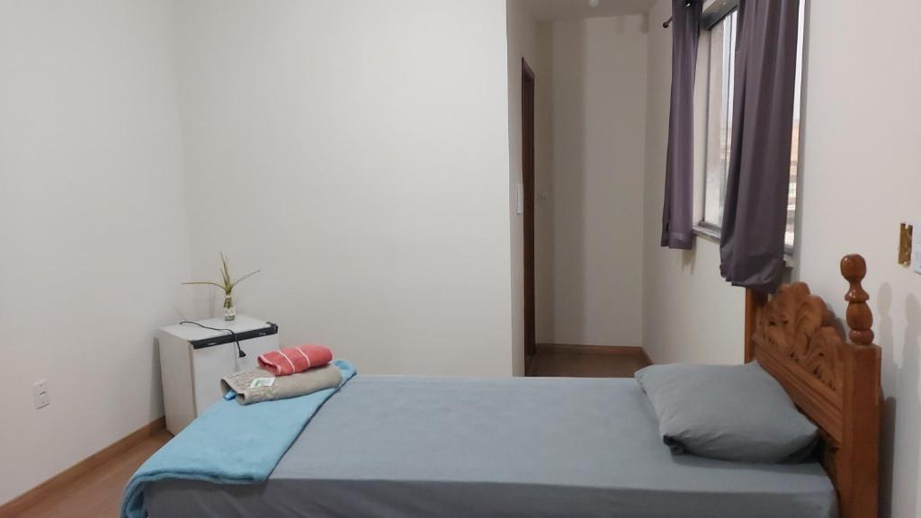 a bedroom with a bed with blue sheets and a window at Star Hotel 209 in Juiz de Fora
