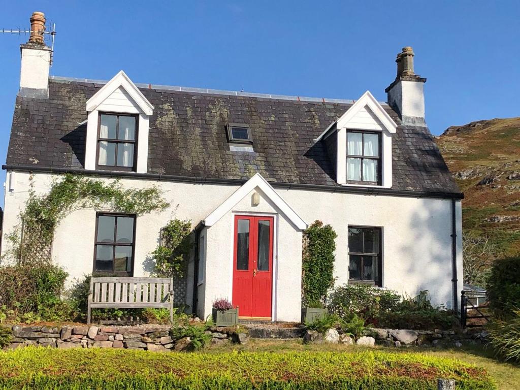 a white house with a red door and a bench at Coulags Croft in Ross on Wye