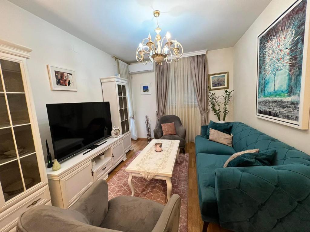 uma sala de estar com um sofá azul e uma televisão em Oscar em Podgorica