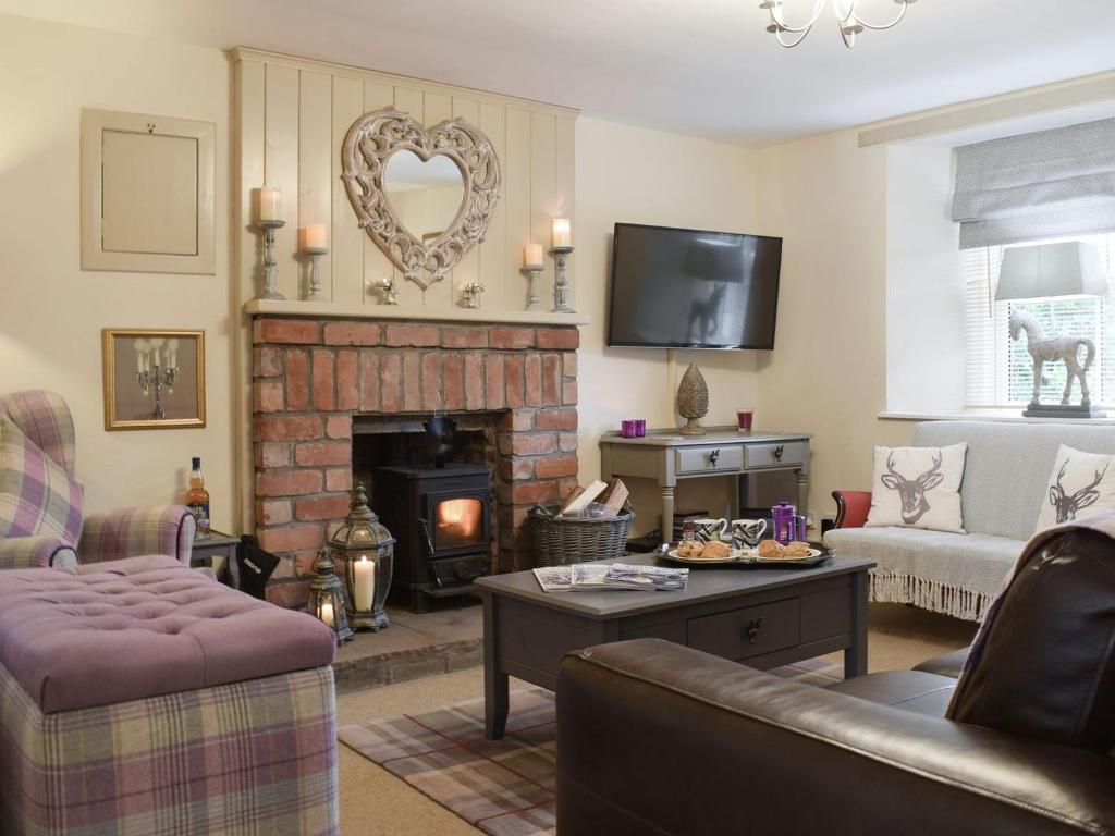 a living room with a couch and a fireplace at Smiddy Cottage in Aberfeldy