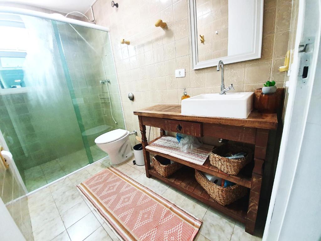 uma casa de banho com um lavatório, um chuveiro e um WC. em Apt com vista para o mar e churrasqueira em Guaratuba