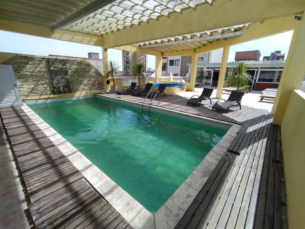 una piscina con sillas y una mesa en una casa en Apart Hotel Sorrento en Santa Teresita
