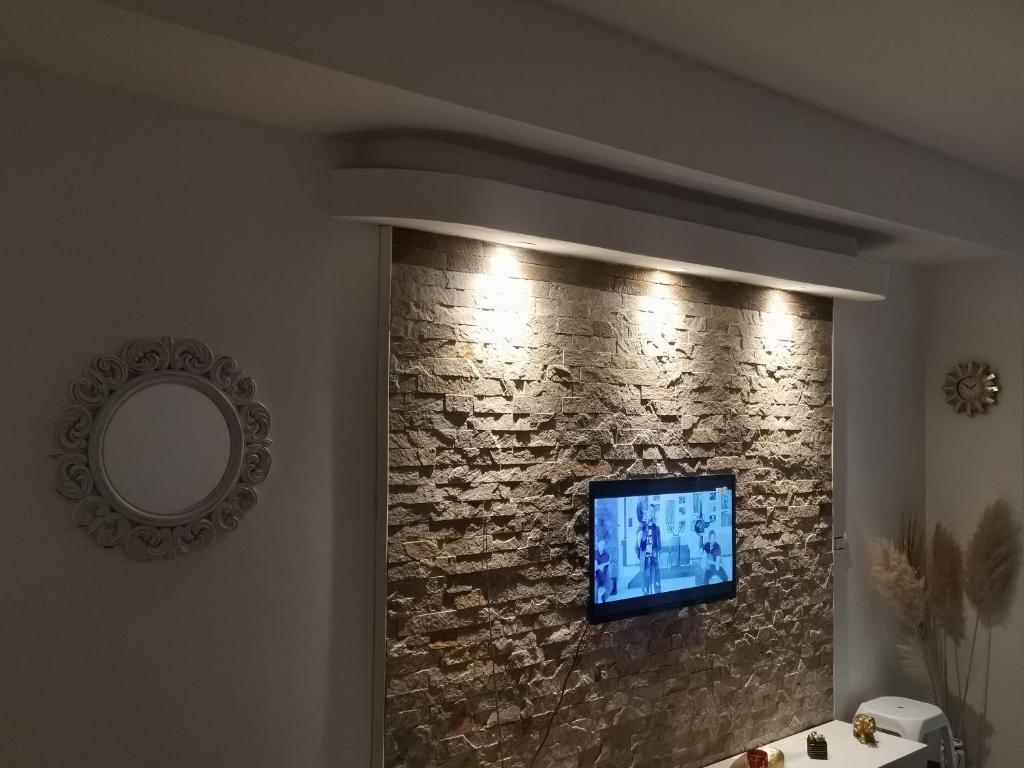 a bathroom with a stone wall with a television on it at Jana apartment 2 in Ohrid