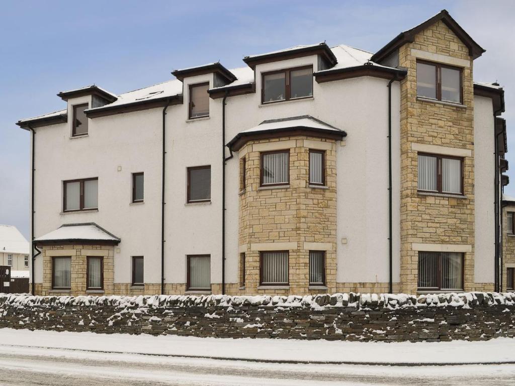 a large white building with snow on top of it at Glen Apartment in Aviemore