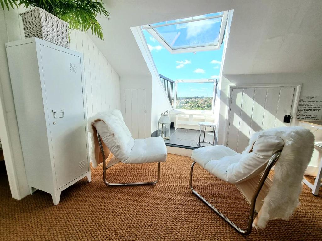 ヘイスティングスにあるWest Hill Retreat Seaview Balconette Loft Apartment with Free Parkingのリビングルーム(白い椅子2脚、窓付)