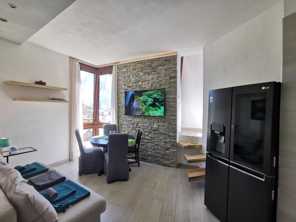 sala de estar con nevera negra y mesa en Flamma Apartment - Ski in & Ski Out, en Breuil-Cervinia