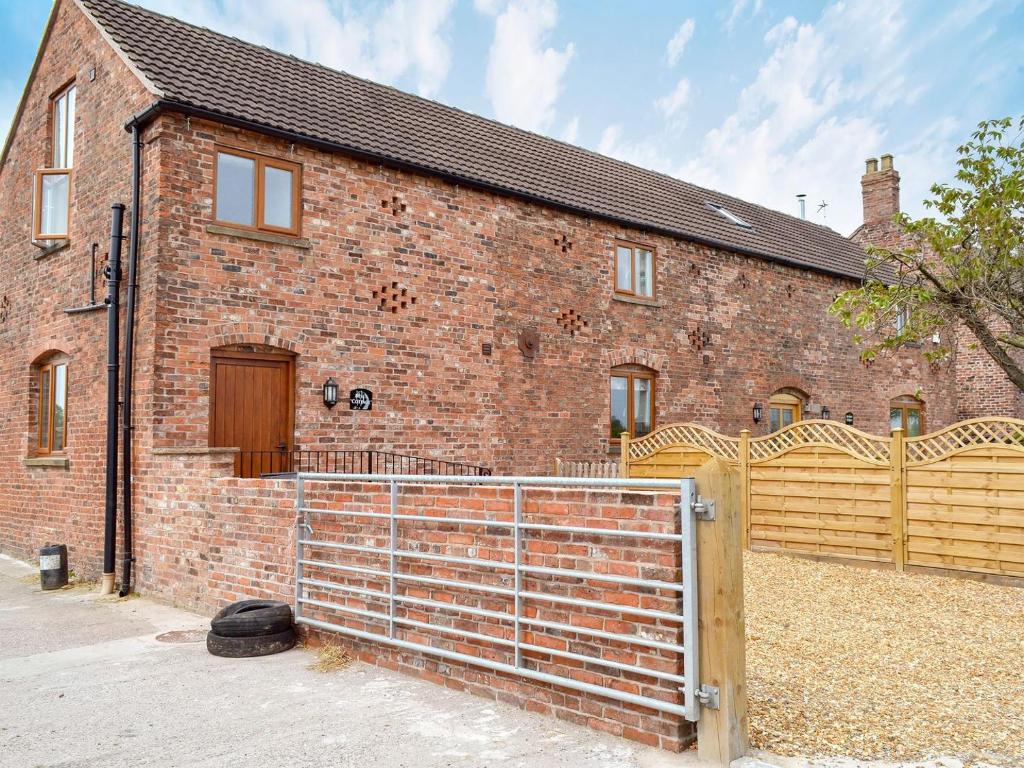a brick house with a fence in front of it at Besss Cottage in Middlewich