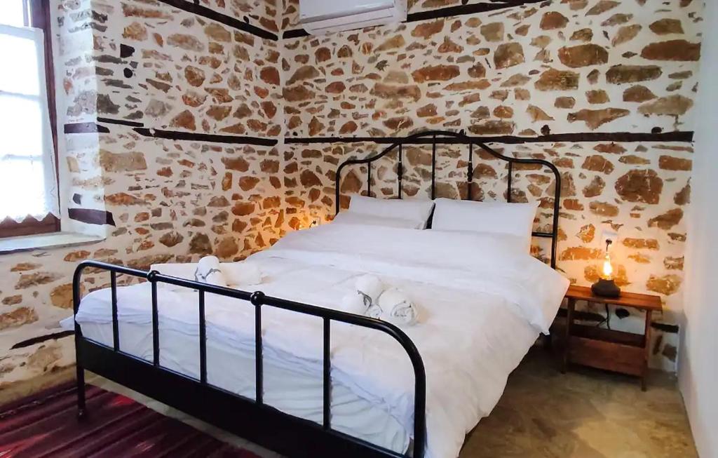 Bett in einem Zimmer mit einer Steinmauer in der Unterkunft San Lorenzo Cottage - Παραδοσιακά Πέτρινα Δωμάτια in Agios Lavrentios