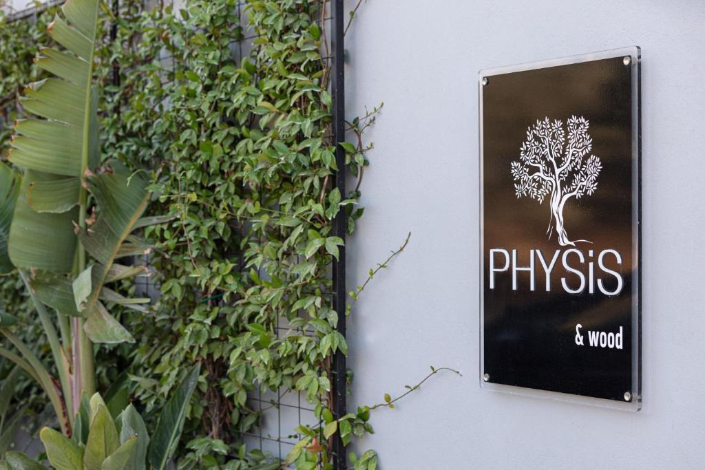 a sign on a wall with a plant at Physis Villas - Metal & Wood in Pigi