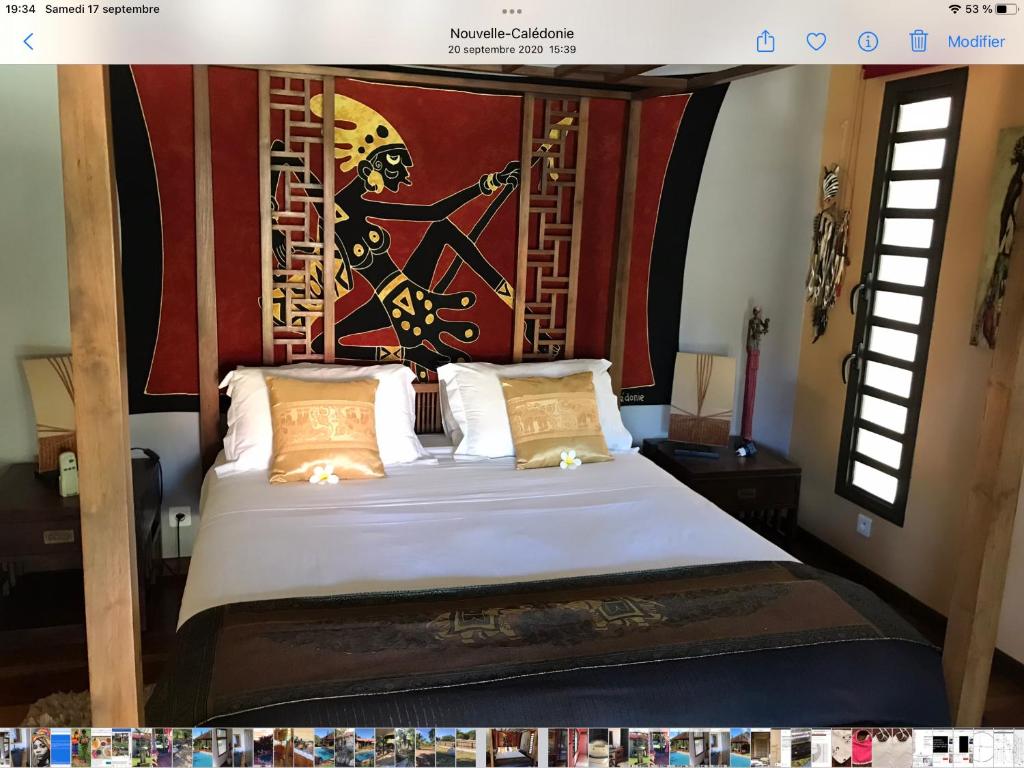 Schlafzimmer mit einem Bett mit Wandgemälde in der Unterkunft Un Temps Pour Soi in Bouloupari