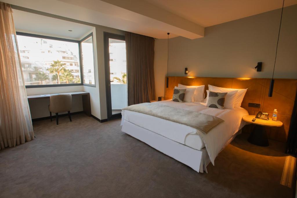 JM Suites Hotel Eco-Friendly Casablanca في الدار البيضاء: غرفة نوم بسرير ابيض كبير ونافذة كبيرة