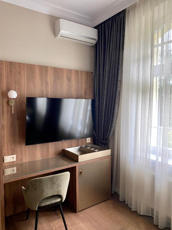 Pokój z telewizorem, krzesłem i biurkiem w obiekcie Pensjonat - Restauracja Żółty Domek w Szczecinku