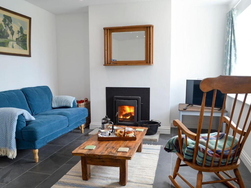a living room with a blue couch and a fireplace at Morolwg in Borth