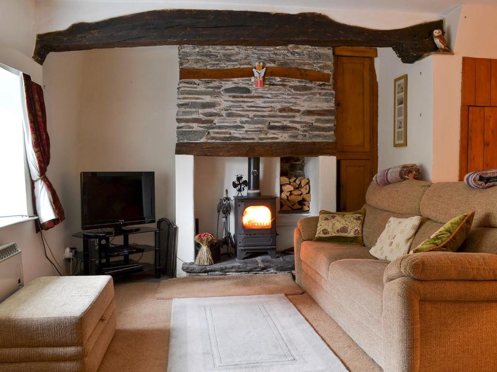 a living room with a couch and a stone fireplace at Taylors Cottage in Threlkeld