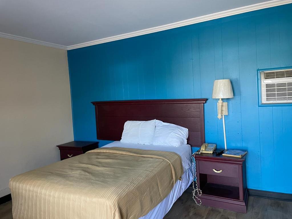 una camera da letto con un letto e una parete blu di Etown Motel a Elizabethtown