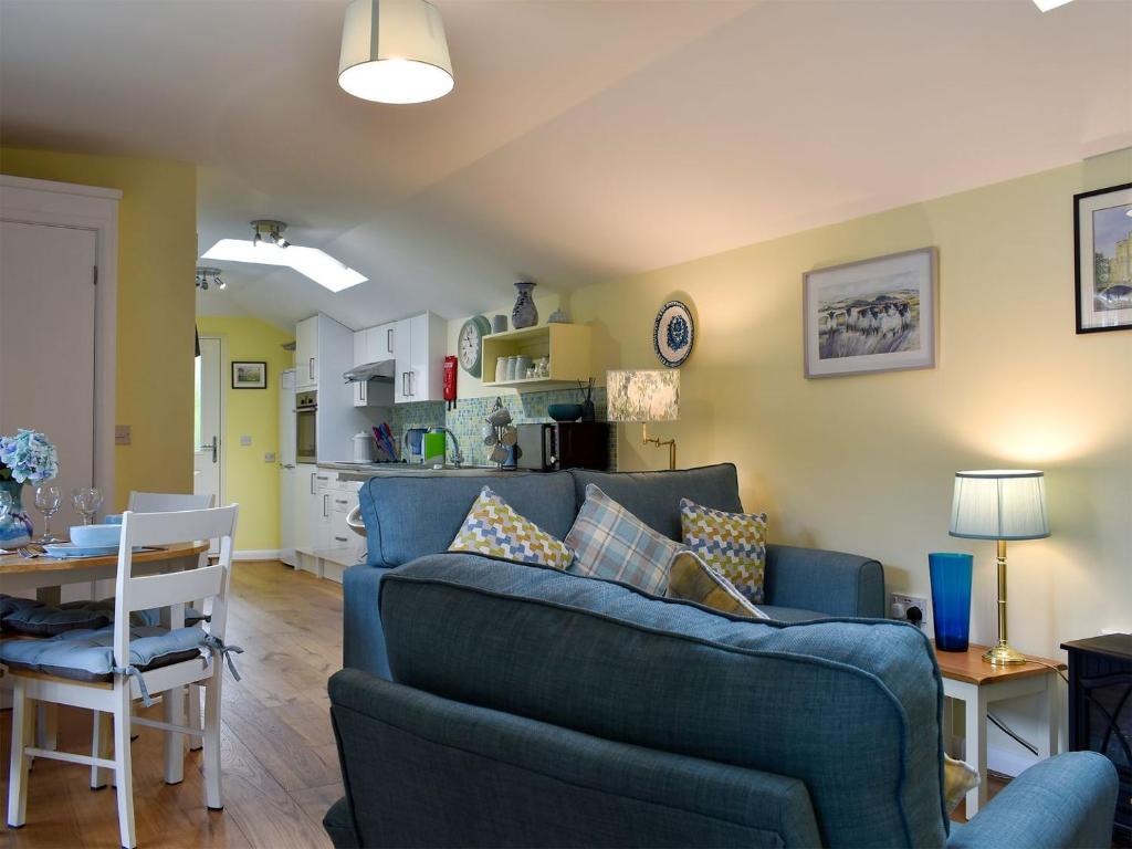 a living room with a blue couch and a kitchen at The Annexe in Barham