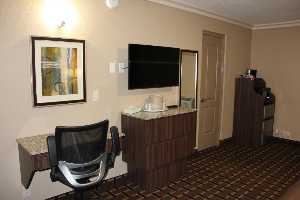 a hotel room with a flat screen tv and a chair at Budget Inn Lake Wales in Lake Wales