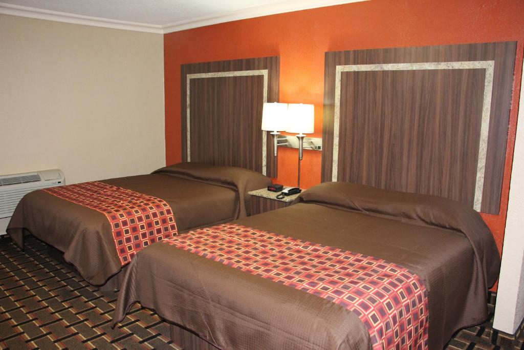 a hotel room with two beds and orange walls at Budget Inn Lake Wales in Lake Wales