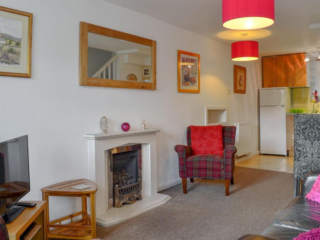 a living room with a fireplace and a red chair at Cosy Nook in Ambleside