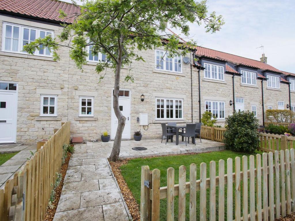 a house with a wooden fence and a yard at Pottergate Mews in Gilling East