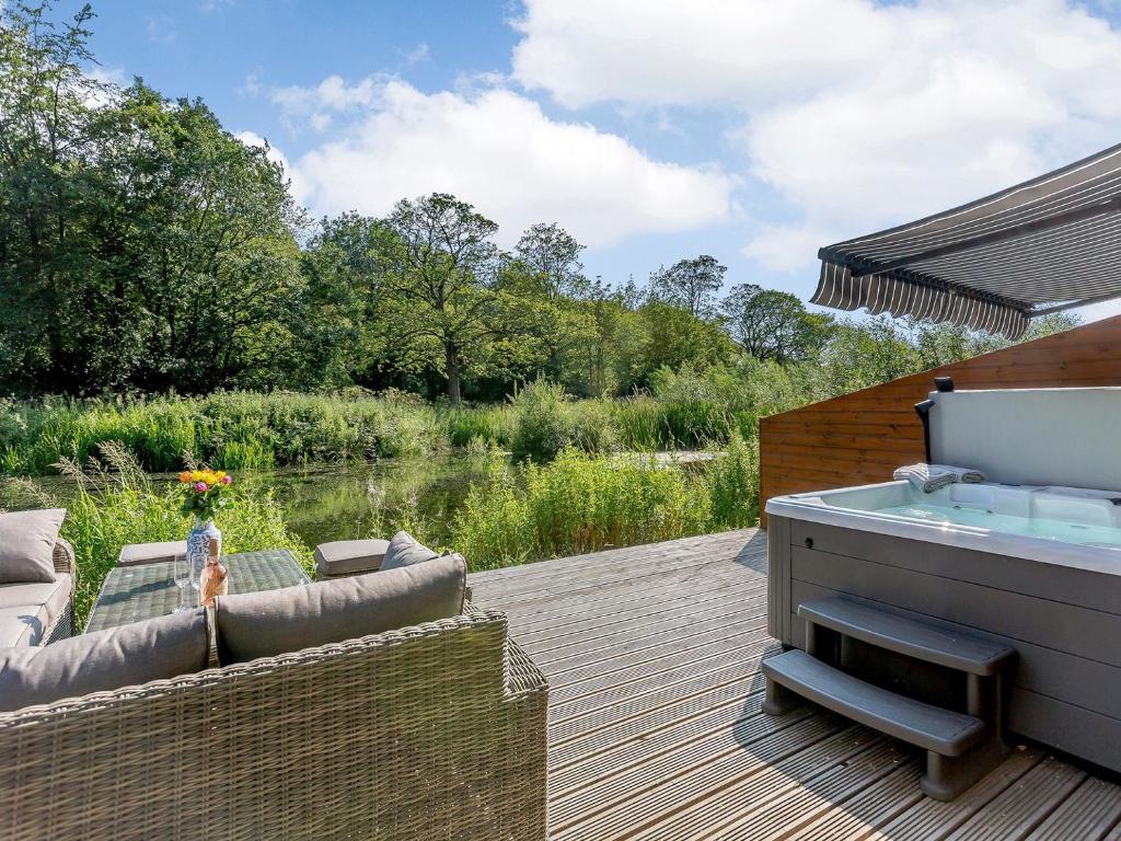 a hot tub sitting on a deck next to a body of water at Waterside Lodge Thirteen - Uk11853 in Southowram