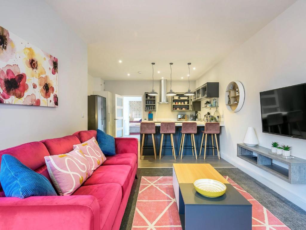 a living room with a red couch and a kitchen at The Old Bank in Mundesley