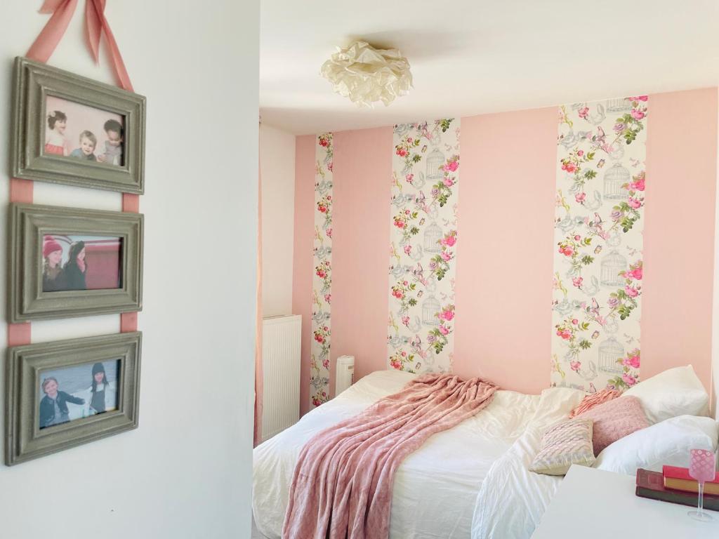 Dormitorio con paredes rosas, cama y cuadros en la pared en Summer in Paris, en Ivry-sur-Seine