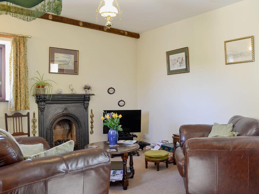 a living room with leather furniture and a fireplace at Swallows Return in Whitehaven