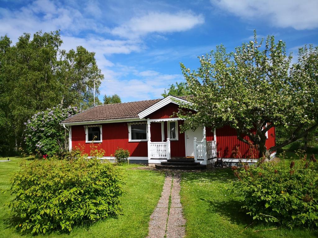 una casa roja con una puerta blanca en un patio en Ferienhaus Vikeberg in Mittelschweden am Meer, en Hållnäs