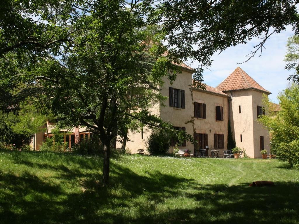 a large house with a tree in the yard at La Bastide du Chêne in Montégut