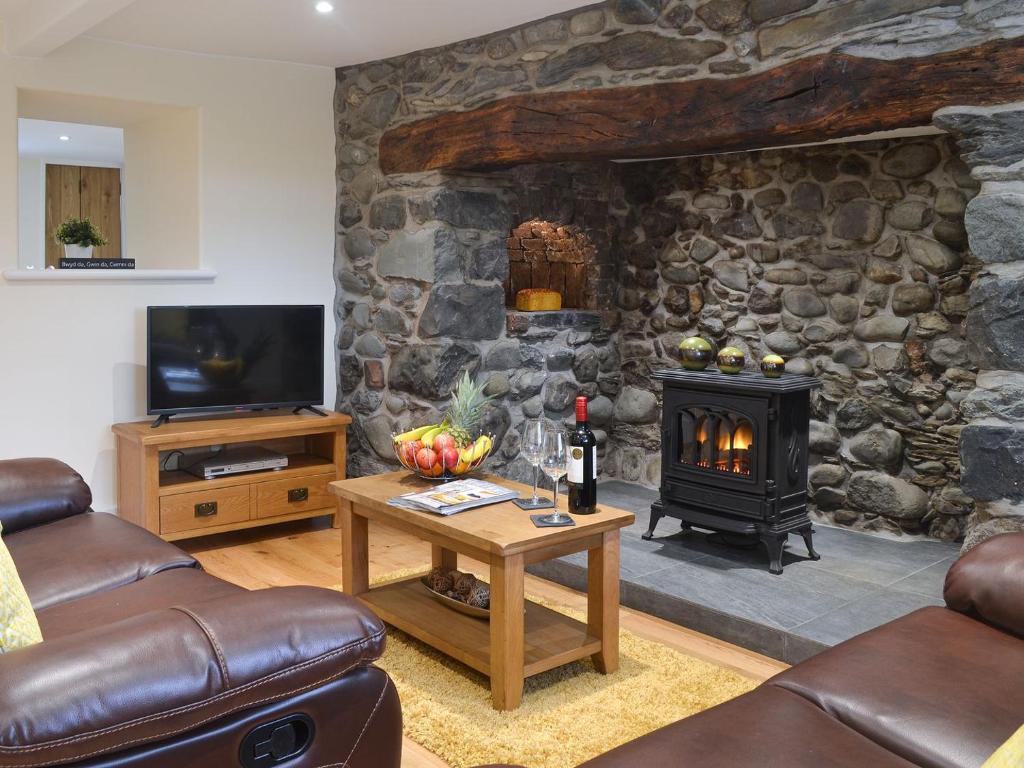 a living room with a stone wall with a fireplace at Pen Parc in Bryn-crug