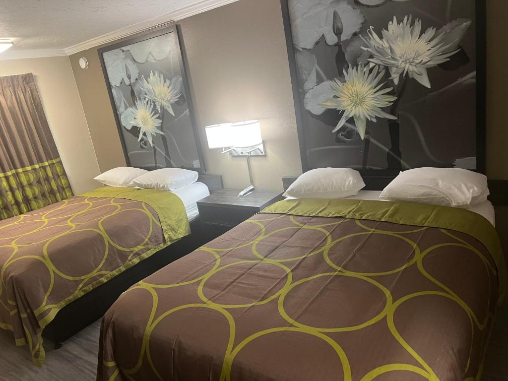 a hotel room with two beds and paintings on the wall at Super 8 by Wyndham Picayune in Picayune