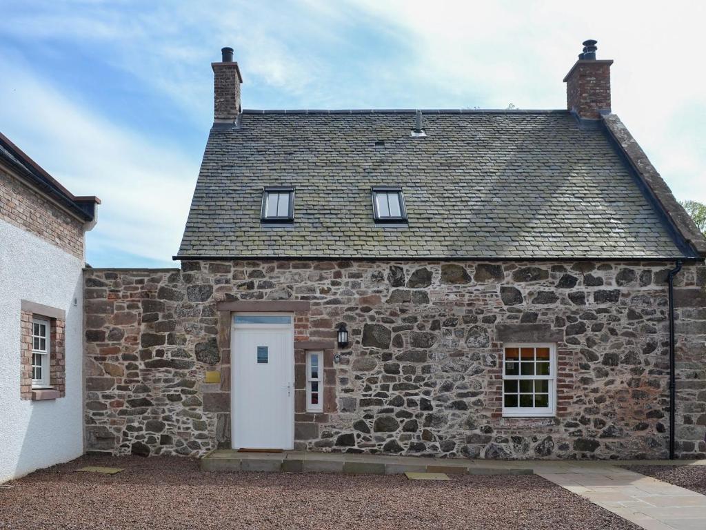 ein altes Steinhaus mit einer weißen Tür und Fenstern in der Unterkunft Grieves Cottage - Uk11107 in Montrose