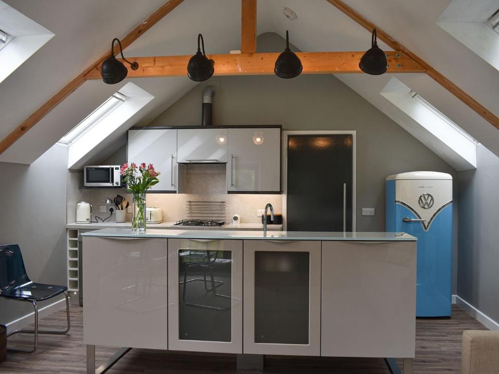 a kitchen with a white island in a loft at Priory Barn in Freshwater