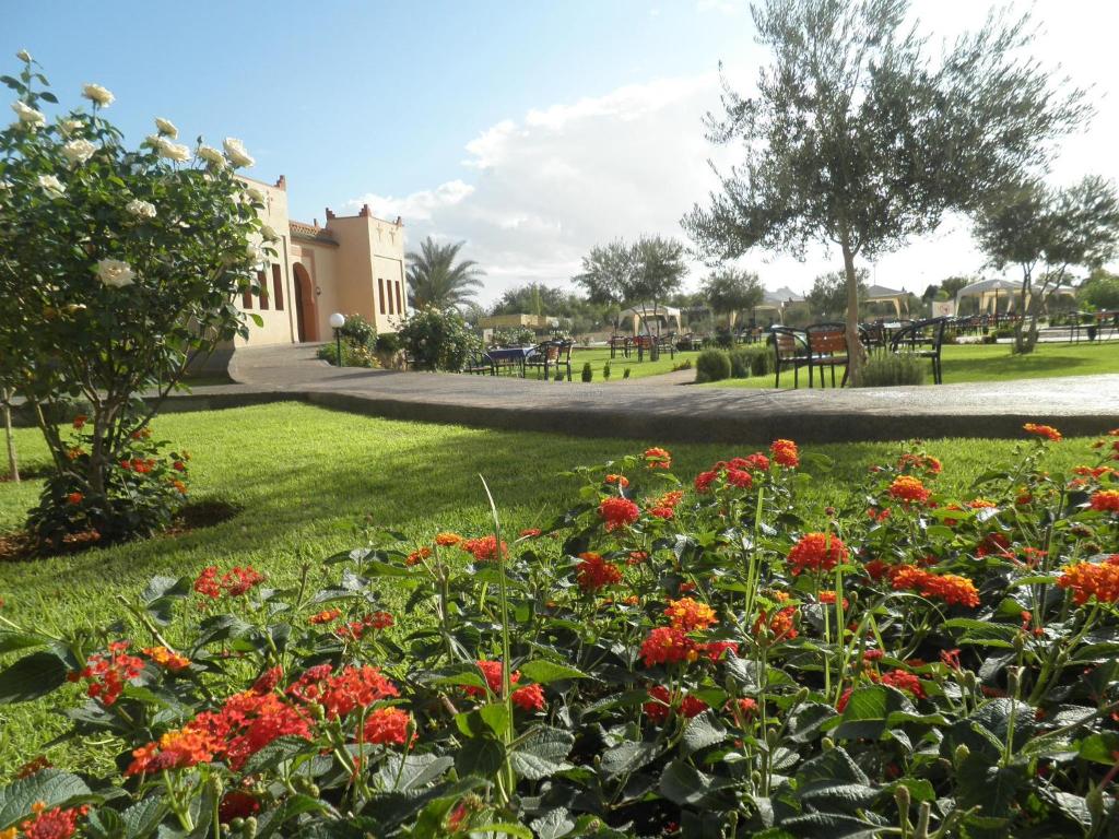 een tuin met rode bloemen in een park bij IGHIZ INN resort in Er Rachidia